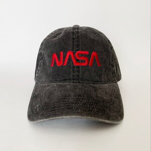 May include: A black distressed baseball cap with a red embroidered NASA logo.