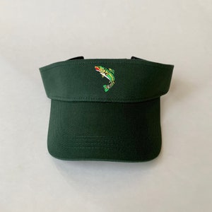 May include: A dark green visor with a small embroidered image of a fish on the front.