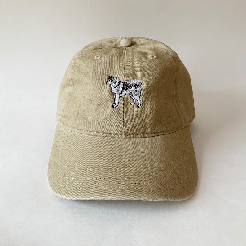 May include: A tan baseball cap with an embroidered image of a black and white husky dog.