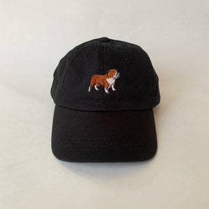 Könnte beinhalten: Schwarze Baseballkappe mit einem gestickten braunen und weißen Bulldoggen.