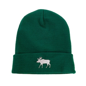 Op de afbeelding: Een groene gebreide beanie met een wit geborduurd elandmotief.