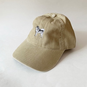 May include: A khaki baseball cap with an embroidered image of a husky dog on the front.