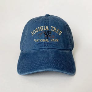 Könnte beinhalten: Eine blaue Baseballkappe aus Denim mit einem gestickten Joshua Tree National Park Logo in Gold und Rot.