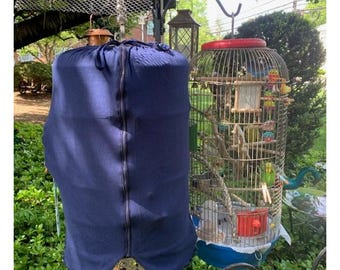 May include: A blue bird cage cover with a zipper, covering a metal bird cage with multiple birds inside. The cage has a red top and a blue base.