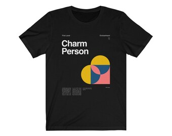 May include: Black t-shirt with a white graphic design that says "Charm Person" and features a heart made of yellow, pink, and blue geometric shapes. The text "First Level" and "Enchantment" are also included in the design.