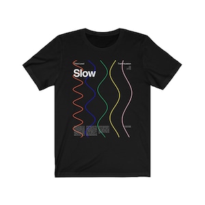 May include: Black t-shirt featuring the word "Slow" in white, with a series of colourful wavy lines. The shirt also has the text "Third Level" and "Transmutation" in white, plus additional text below the lines.