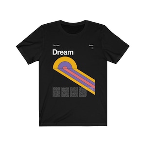 May include: Black t-shirt with a graphic design featuring a yellow, purple, and pink abstract shape with the word "Dream" in white text above it. The text "Fifth Level" and "Illusion" are also included in the design.