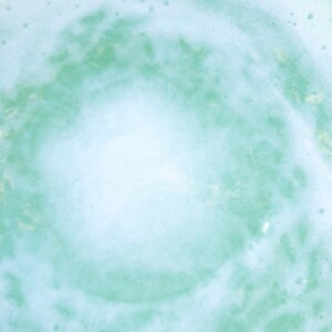 May include: A close-up of a light blue and white foamy texture with a circular pattern in the center.