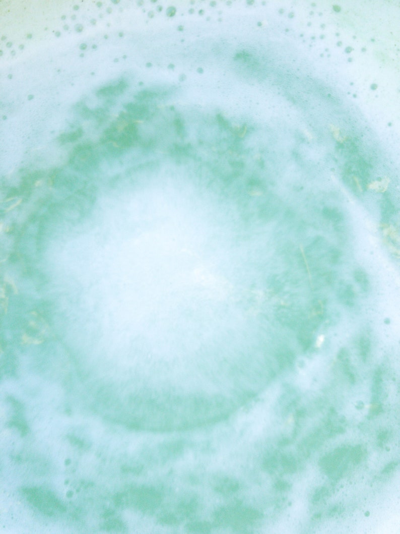 May include: A close-up of a light blue and white foamy texture with a circular pattern in the center.
