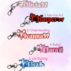 May include: A selection of keyrings featuring names and sport-related designs. Keyrings for gymnastics (Olivia), martial arts (Harper), cheerleading (Ivanna), ballet (Clara), and ice skating (Elsa). Each keyring has a silver clasp.