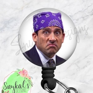 Könnte beinhalten: Ein runder Ausweishalter mit dem aufgedruckten Bild einer Person, die ein violettes Bandana mit weißem Paisleymuster über einem dunklen Anzug mit Krawatte trägt. Der Ausweishalter hat eine schwarze Einzugsschnur und eine transparente Lasche.