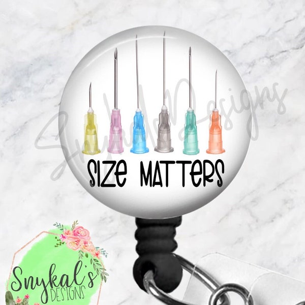May include: A circular badge reel featuring a graphic of six hypodermic needles with yellow, pink, blue, grey, teal, and orange hubs. The text "SIZE MATTERS" is printed in black below the needles. The reel has a black plastic housing and a metal clip.