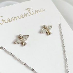 以下が含まれることがあります： 白いカードに「trementina」という文字が筆記体で書かれた、透明なクリスタルアクセントが付いたシルバーのエンジェルイヤリングのペアです。