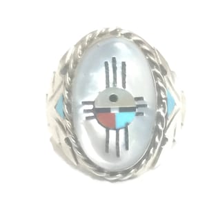 May include: A silver ring with a white mother of pearl inlay featuring a turquoise, red, and black Southwest design. The ring has a rope-like border.