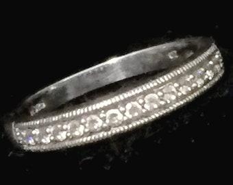 May include: A silver band ring with a row of small diamonds set in a delicate design.