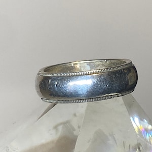 May include: A silver wedding band with a rounded profile and a slightly textured surface.