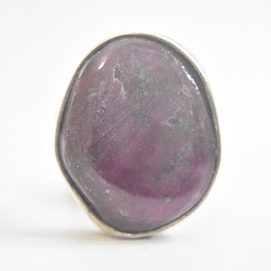 May include: A silver ring with a large, oval-shaped, purple gemstone.