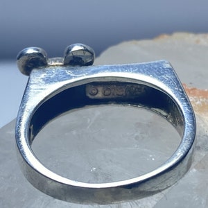Puede incluir: Anillo de plata con un dise&ntilde;o de cabeza de Mickey Mouse. El anillo est&aacute; marcado con el texto "&copy; Disney".