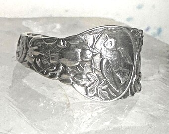 May include: A silver spoon ring with a detailed design of birds and leaves. The ring is made from a recycled spoon and is a unique piece of jewelry.
