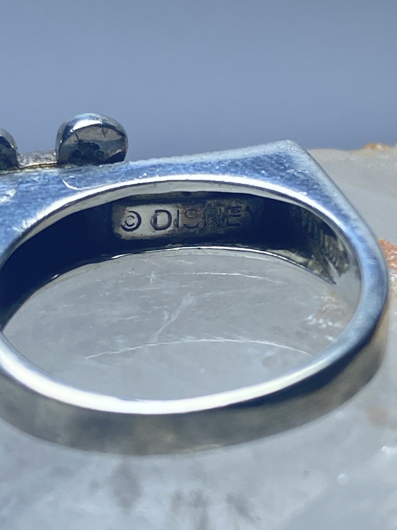 Puede incluir: Un anillo de plata con un dise&ntilde;o de Mickey Mouse. El anillo est&aacute; inscrito con el s&iacute;mbolo de copyright y la palabra "DISNEY".