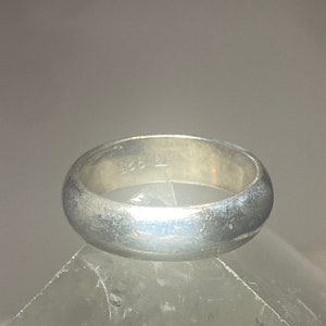 May include: A silver band ring with a smooth, polished finish. The inside of the band is marked with the number "925".