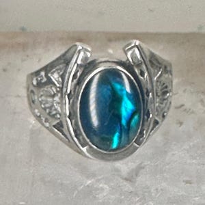 May include: A silver ring with a blue abalone shell horseshoe design.