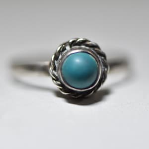 May include: A silver ring with a turquoise stone set in a twisted wire design.