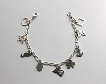 May include: A silver charm bracelet with a variety of charms, including a crown, a seahorse, a hamsa hand, a four-leaf clover, an anchor, a square, and a butterfly.