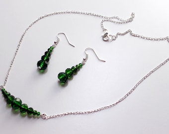 Set di gioielli con perline di vetro verde, collana e orecchini color argento.