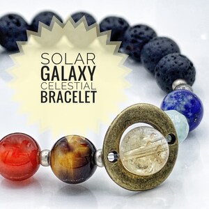 May include: A celestial bracelet with a gold-toned charm featuring a circle with a smaller circle inside. The bracelet is made with lava rock, carnelian, tiger's eye, aquamarine, lapis lazuli, and clear quartz beads. The bracelet is called "Solar Galaxy Celestial Bracelet".