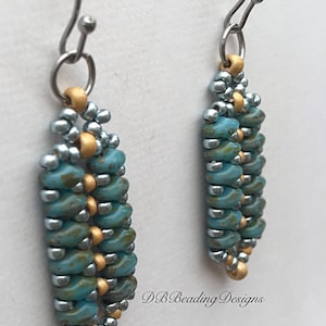 May include: A pair of dangle earrings with a silver and gold beaded design. The beads are a mix of turquoise and silver with gold accents. The earrings are hanging from silver hooks.