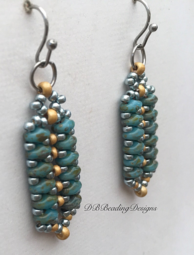 May include: A pair of dangle earrings with a silver and gold beaded design. The beads are a mix of turquoise and silver with gold accents. The earrings are hanging from silver hooks.