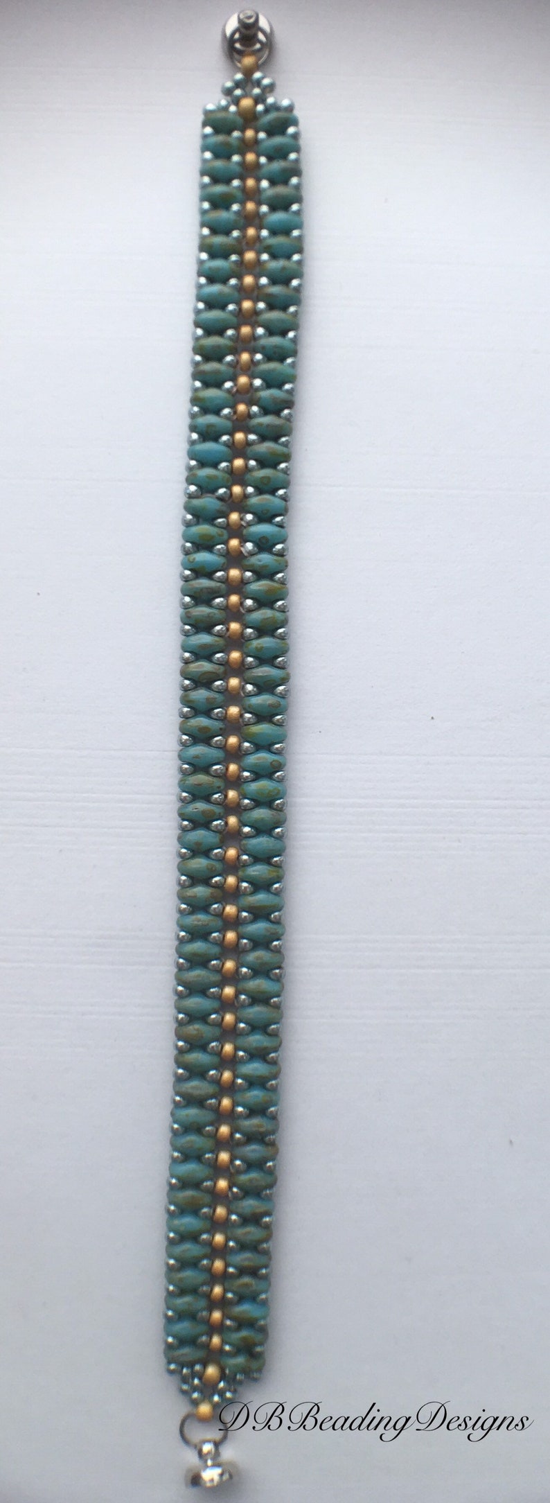 May include: A turquoise and gold beaded bracelet with a silver clasp. The bracelet is made with small, round beads and has a simple, elegant design.