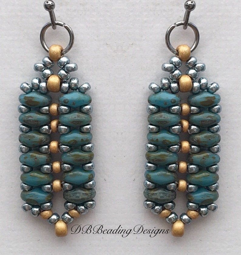 May include: A pair of dangle earrings with a geometric design. The earrings are made with turquoise, silver, and gold beads. The earrings are approximately 2 inches long.