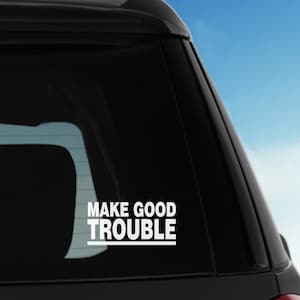 Può includere: Un'auto nera con un adesivo in vinile bianco sul lunotto posteriore che dice "MAKE GOOD TROUBLE".