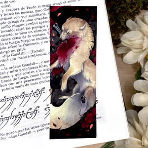 Puede incluir: Marcapáginas con una ilustración a la acuarela de dos lobos. Uno es marrón claro, el otro blanco. El lobo marrón claro tiene un hueso en la boca, rodeado de rosas rojas. El marcapáginas es rectangular.
