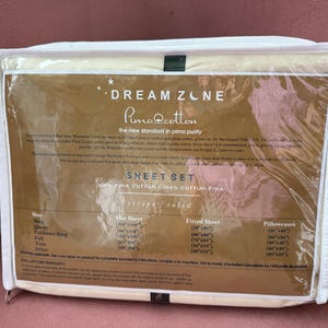 May include: Cream-colored Dream Zone Pima Cotton sheet set in a clear plastic package. The packaging features text including "Dream Zone" and "Pima Cotton". The sheet set includes a flat sheet, fitted sheet, and pillowcases.