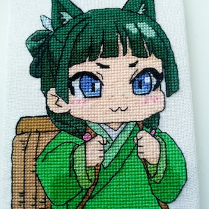 Könnte beinhalten: Kreuzstich-Stickerei eines Anime-Charakters mit grünen Haaren und Katzenohren, der ein grünes Kimono trägt und eine braune Tasche trägt. Der Charakter hat große blaue Augen und einen kleinen, lächelnden Mund. Die Stickerei ist unten rechts mit "Stitchopia" signiert.