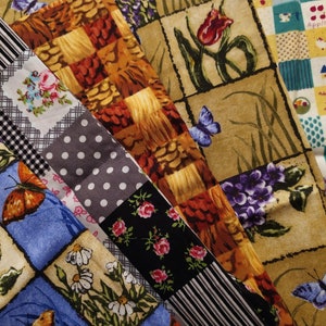 Pode incluir: Um mosaico de retalhos de tecido com vários padrões florais, geométricos e inspirados na natureza. Os tecidos são em tons de marrom, azul, preto, branco e verde. Os tecidos são dispostos em um padrão aleatório, criando um design único e colorido.