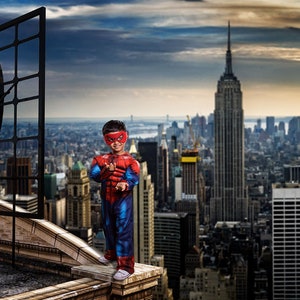 以下が含まれることがあります： スパイダーマンの衣装を着た子供が、ニューヨーク市のスカイラインを見下ろす屋上に立っています。背景にはエンパイアステートビルが見えます。