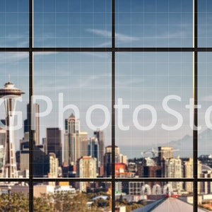 Puede incluir: Una vista del horizonte de Seattle a trav&eacute;s de una gran ventana con un patr&oacute;n de cuadr&iacute;cula. La Space Needle es visible en el centro de la imagen, con otros rascacielos y edificios en el fondo. Una cordillera es visible en la distancia.
