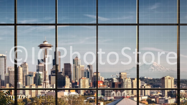 Puede incluir: Una vista del horizonte de Seattle a trav&eacute;s de una gran ventana con un patr&oacute;n de cuadr&iacute;cula. La Space Needle es visible en el centro de la imagen, con otros rascacielos y edificios en el fondo. Una cordillera es visible en la distancia.