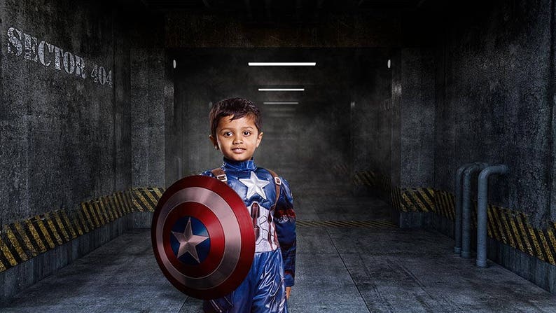 May include: A young boy dressed as Captain America stands in a dark, industrial hallway. He is holding a red, white, and blue shield in his left hand. The hallway is marked with yellow and black warning stripes. The text "Sector 404" is visible on the wall.