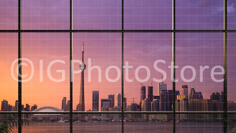 Puede incluir: Una vista del horizonte de Toronto al atardecer, vista a trav&eacute;s de una gran ventana con un patr&oacute;n de cuadr&iacute;cula. La Torre CN es el edificio m&aacute;s alto del horizonte, y otros rascacielos son visibles en la distancia.