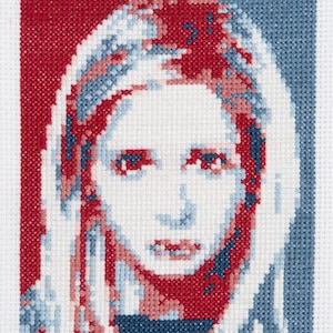 May include: Cross-stitch artwork featuring a portrait of a woman with red and blue hair, with the word "SLAY" in blue lettering below the portrait.