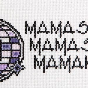 May include: A white cross-stitch design featuring a purple and white disco ball with the text "Mama Se Mama Sa Mamakosa" in black.