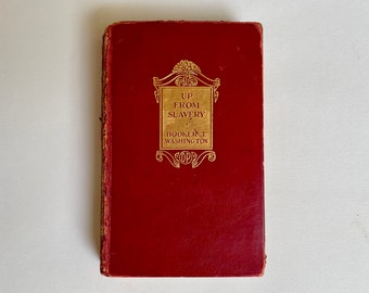 May include: A red hardcover book with gold lettering on the front cover. The title is "Up From Slavery" by Booker T. Washington.