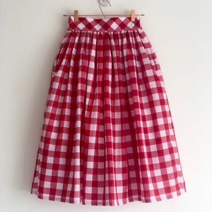 Könnte beinhalten: Ein roter und weißer Gingham-Midi-Rock mit gerafftem Bund und Taschen.