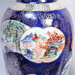 May include: A blue and white porcelain vase with gold accents and a floral design. The vase features a scene of a Japanese garden with a pagoda and trees.