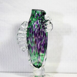 May include: A green and purple glass vase with a clear glass base and clear glass wings. The vase has a spotted pattern.